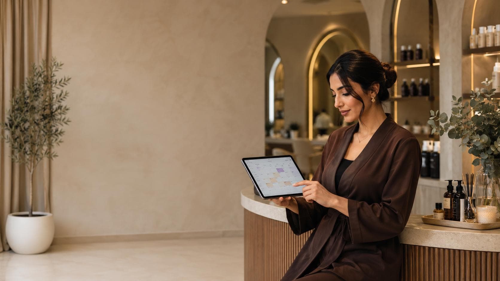 Wellness business owner reviewing appointments on a tablet in a premium salon.
